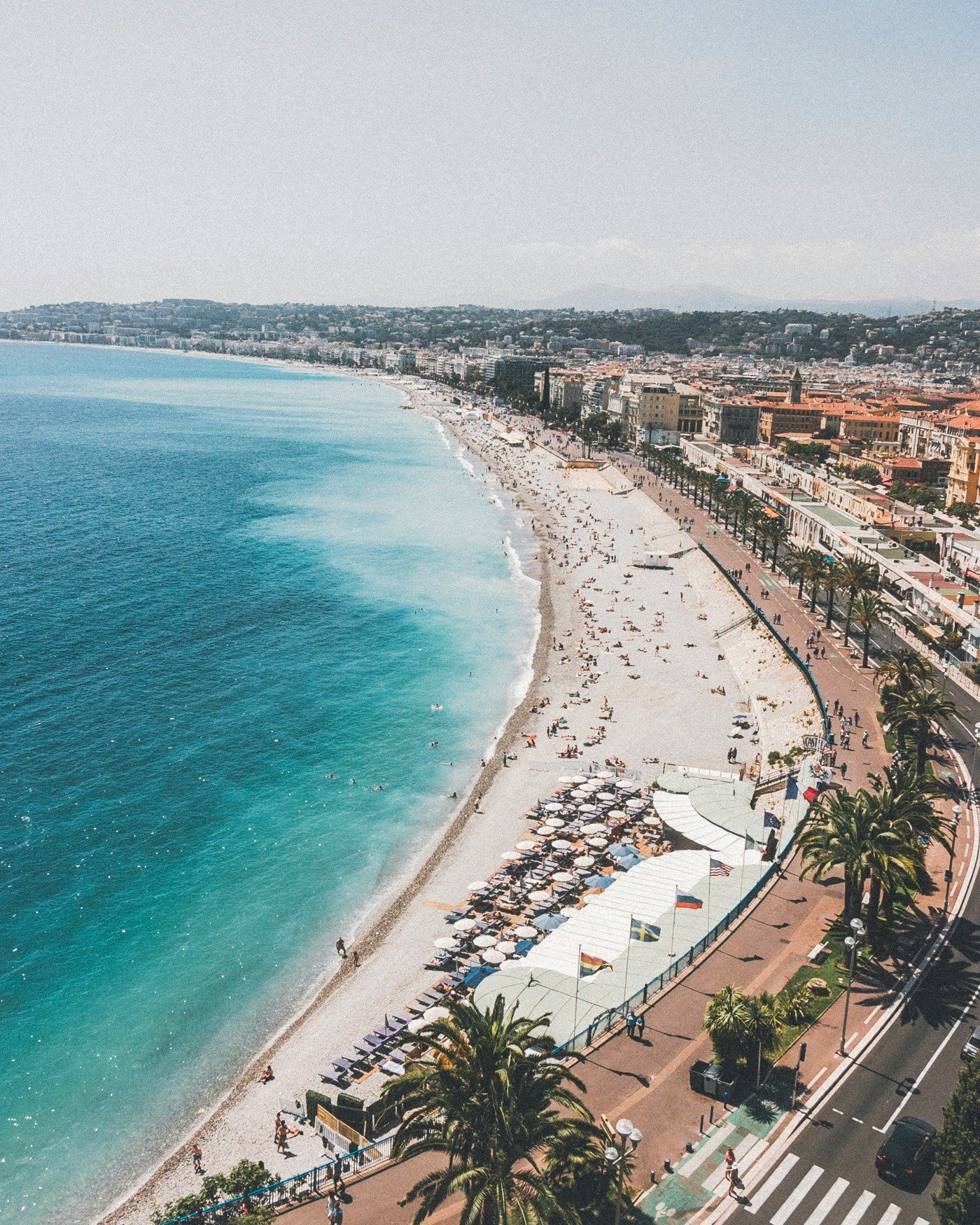 Aerial view of the Baie des Anges in Nice, turquoise water and a half-empty beach in early September