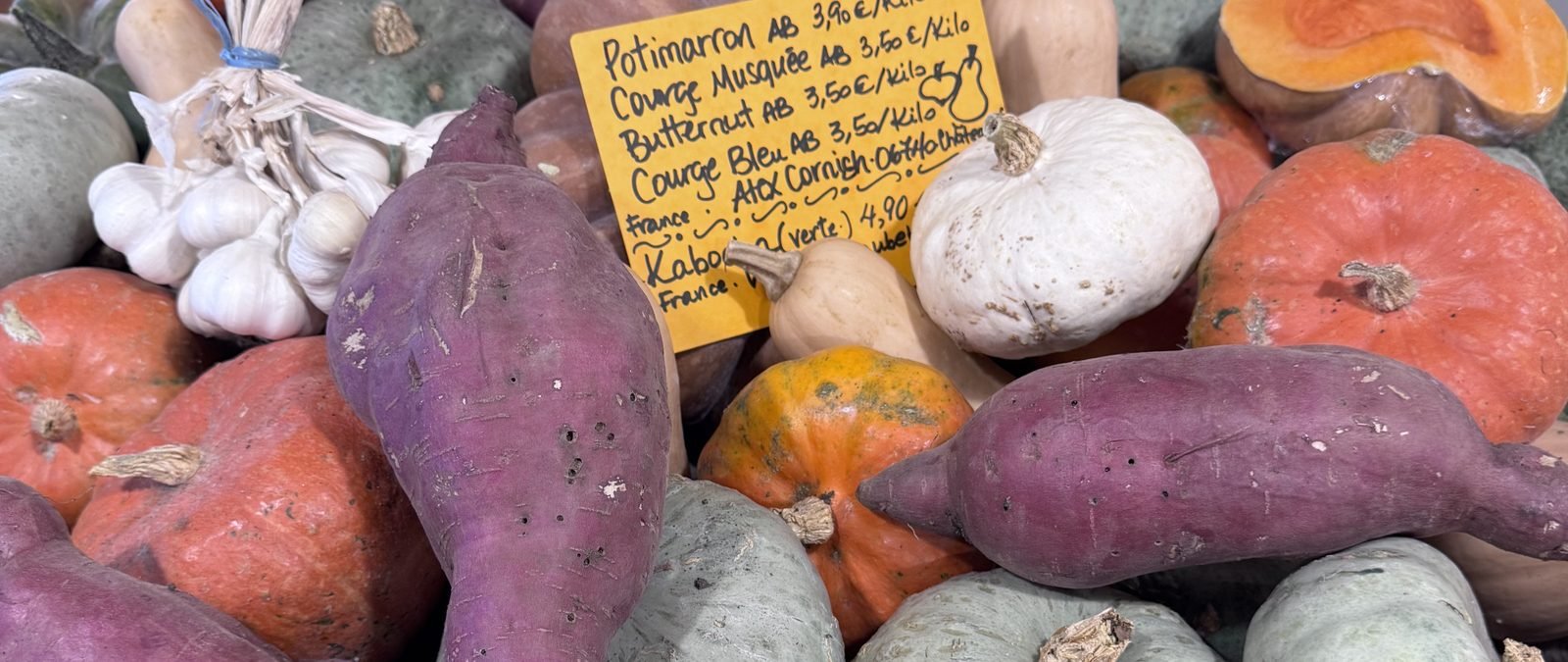 An autumn market stall or table: cèpes, chestnuts, squash, a glass of red.